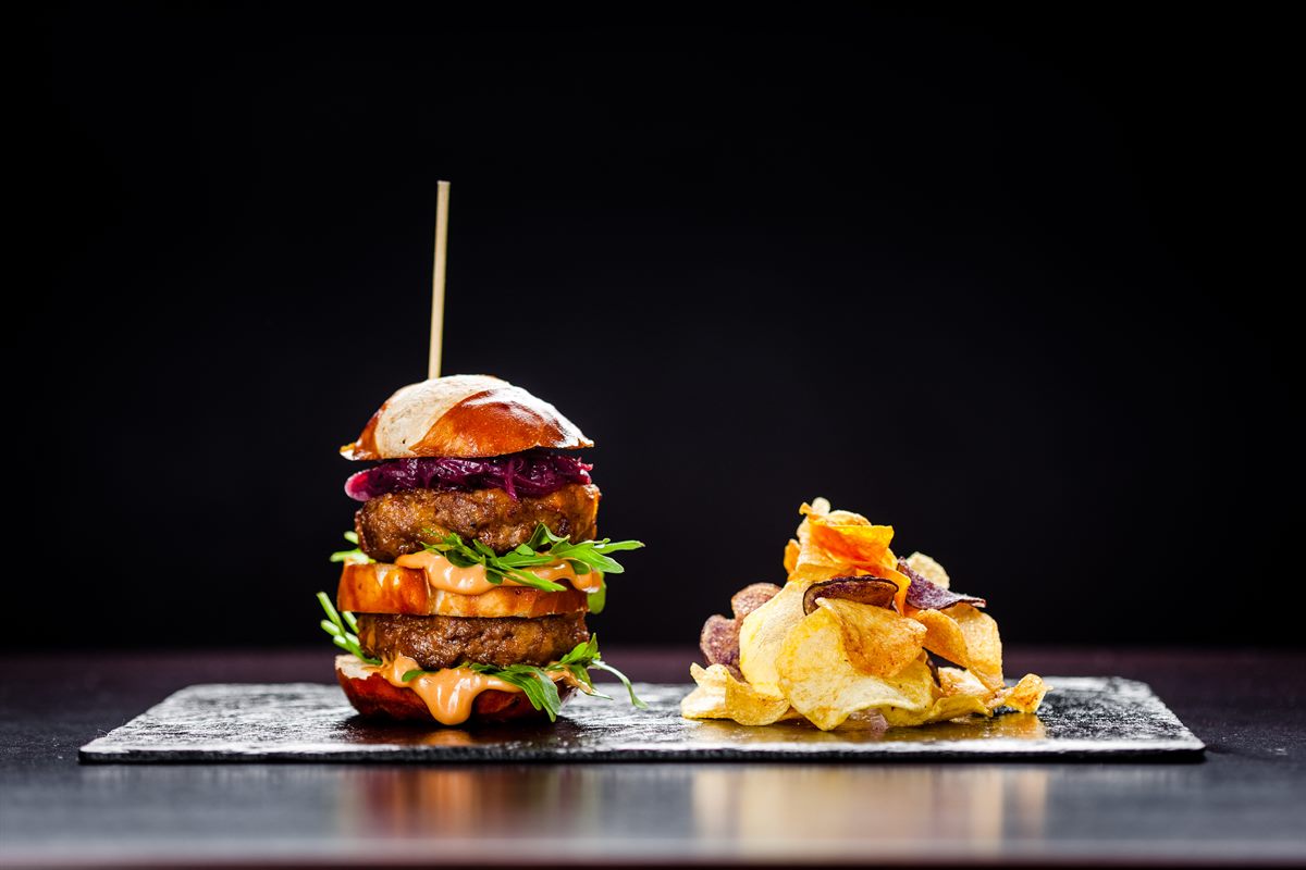 Sans Souci Burger: Laugenweckerl | Rindfleisch | Cocktailsauce | Rucola | Zwiebel | Cheddar | Gemüsechips